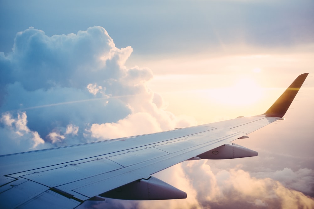 An aeroplane wing above the clouds at sunset, representing curated travel privileges