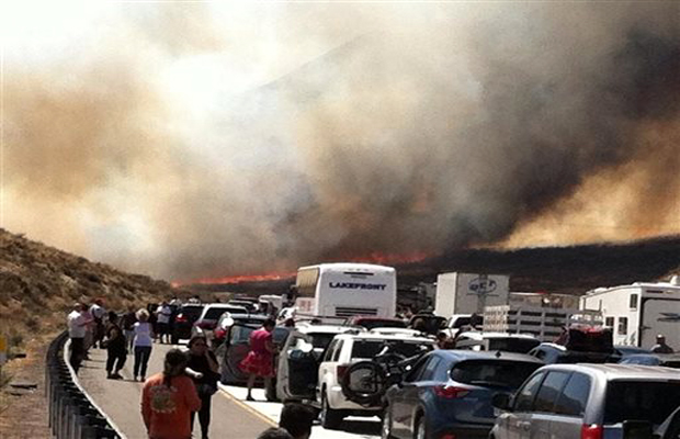 Bystanders look on along Interstate 15 on the Cajon Pass, Friday, July 17, 2015, near San Bernadino, Calif., as a fast-moving wildfire swept across the Southern California freeway, destroying numerous vehicles and sending motorists running to safety Bystanders look on along Interstate 15 on the Cajon Pass, Friday, July 17, 2015, near San Bernadino, Calif., as a fast-moving wildfire swept across the Southern California freeway, destroying numerous vehicles and sending motorists running to safety
