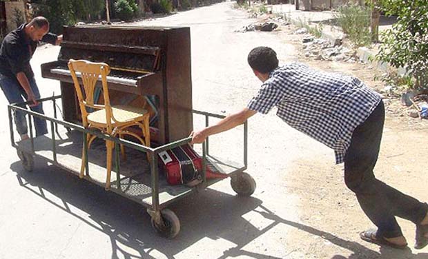 A file picture showing Aeham al-Ahmad, being helped by a friend to push his piano along a the street in the southern Damascus suburb. (Photo: AFP) A file picture showing Aeham al-Ahmad, being helped by a friend to push his piano along a the street in the southern Damascus suburb. (Photo: AFP)