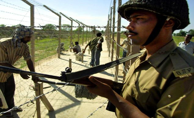 A BSF personnel stands guard as labourers fence the international border at the Samba sector. (Photo: AP) A BSF personnel stands guard as labourers fence the international border at the Samba sector. (Photo: AP)