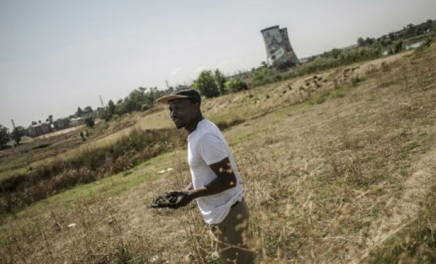 South African artist Mzi Gojo holds some cow dung he uses for his artwork near the cooling towers of Orlando Power Station on October 1, 2015 in Soweto, South Africa. (Picture Courtesy: AFP) South African artist Mzi Gojo holds some cow dung he uses for his artwork near the cooling towers of Orlando Power Station on October 1, 2015 in Soweto, South Africa. (Picture Courtesy: AFP)