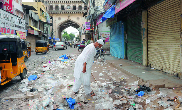 A man cleans his shop and empties the garbage on the road in the backdrop of Charminar. (Photo: DC) A man cleans his shop and empties the garbage on the road in the backdrop of Charminar. (Photo: DC)