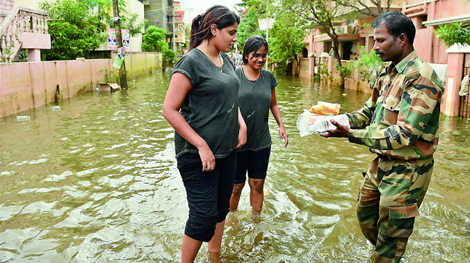 Two girls collect relief material from an Army jawan in Velachery, one of the worst flood-hit areas in Chennai (Photo: PTI) Two girls collect relief material from an Army jawan in Velachery, one of the worst flood-hit areas in Chennai (Photo: PTI)