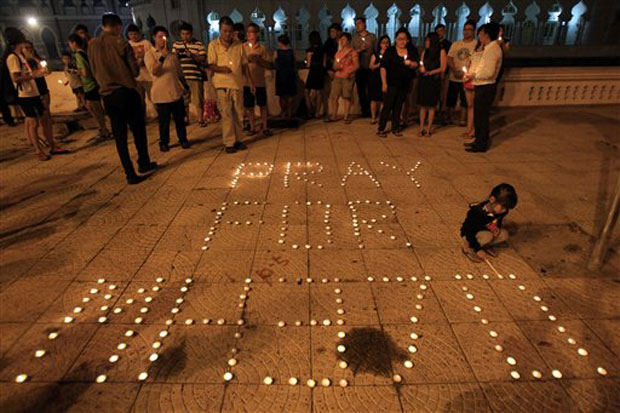 A girl lights a candle next to a message reading "Pray for MH370" during a candlelight vigil for passengers aboard a missing Malaysia Airlines plane in Kuala Lumpur. Photo- AP A girl lights a candle next to a message reading "Pray for MH370" during a candlelight vigil for passengers aboard a missing Malaysia Airlines plane in Kuala Lumpur. Photo- AP