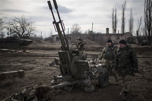 Ukrainian soldiers walk past weapons near Debaltseve, eastern Ukraine, Sunday, Feb. 8, 2015. The government-held town of Debaltseve, a key railway junction, has been the epicenter of recent battles between Russian-backed separatists and Ukrainian Ukrainian soldiers walk past weapons near Debaltseve, eastern Ukraine, Sunday, Feb. 8, 2015. The government-held town of Debaltseve, a key railway junction, has been the epicenter of recent battles between Russian-backed separatists and Ukrainian