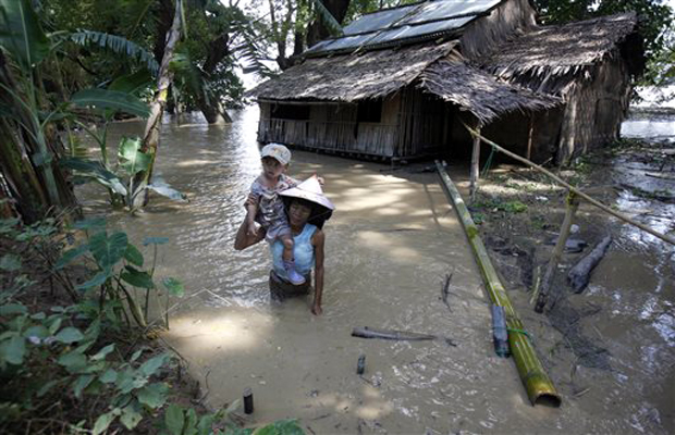 A woman carrying her child wades through floodwaters near a half-submerged residence in Hinthada township, Ayeyarwaddy delta, Myanmar. The number of people affected by flooding across Myanmar was approaching 1 million on Sunday, with waters in the A woman carrying her child wades through floodwaters near a half-submerged residence in Hinthada township, Ayeyarwaddy delta, Myanmar. The number of people affected by flooding across Myanmar was approaching 1 million on Sunday, with waters in the
