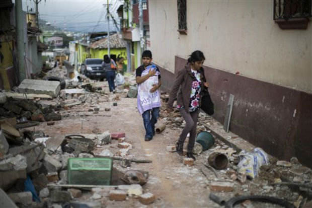 A Family walks trough a street littered with the rubble from buildings that fell during an earthquake in San Pedro, Guatemala, on Monday. (Photo: AP) A Family walks trough a street littered with the rubble from buildings that fell during an earthquake in San Pedro, Guatemala, on Monday. (Photo: AP)