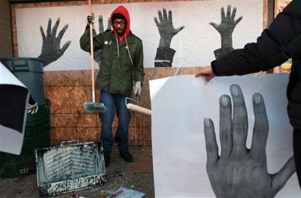 St. Louis artist Damon Davis hangs his photographs of hands to cover the plywood-covered windows at the Ferguson Market on Wednesday, in Ferguson, Missouri. (Photo: AP) St. Louis artist Damon Davis hangs his photographs of hands to cover the plywood-covered windows at the Ferguson Market on Wednesday, in Ferguson, Missouri. (Photo: AP)