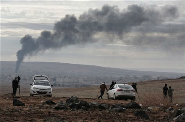 Members of the media on a hilltop on the outskirts of Suruc, at the Turkey-Syria border, watch as smoke from a fire rises following a strike in Kobani, Syria, during fighting between Syrian Kurds and the militants of Islamic State group, Sunday. ( Members of the media on a hilltop on the outskirts of Suruc, at the Turkey-Syria border, watch as smoke from a fire rises following a strike in Kobani, Syria, during fighting between Syrian Kurds and the militants of Islamic State group, Sunday. (
