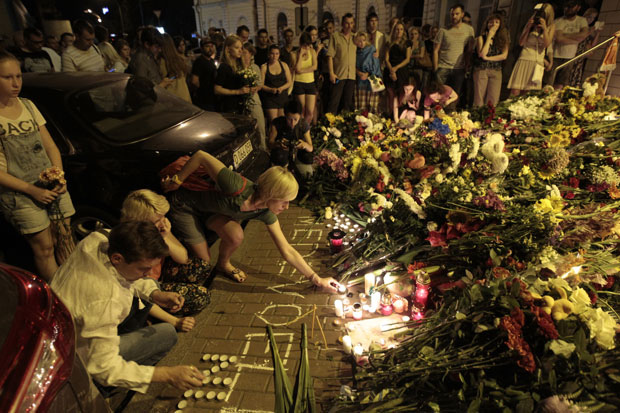 People hold candles and place flower tribute to commemorate victims of Malaysia Airlines plane crash. Photo: AP People hold candles and place flower tribute to commemorate victims of Malaysia Airlines plane crash. Photo: AP