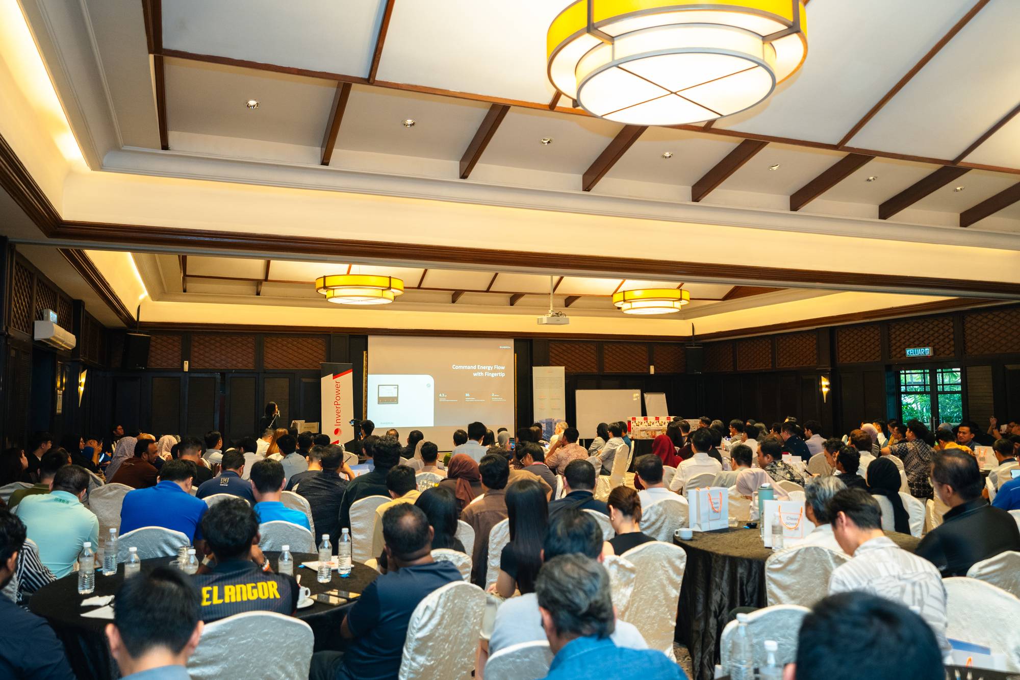 A full ballroom of seated attendees at round tables facing a presentation screen during the InverPower session at The Saujana