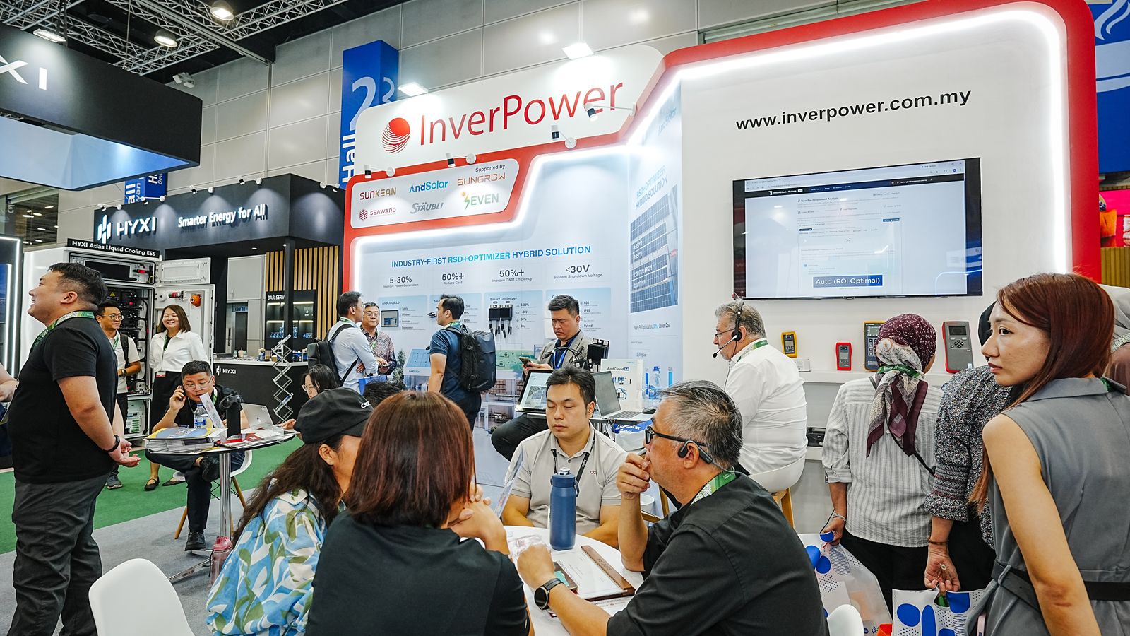 Visitors in a meeting at the round table of the InverPower booth at iGEM 2026, with the partner wall behind