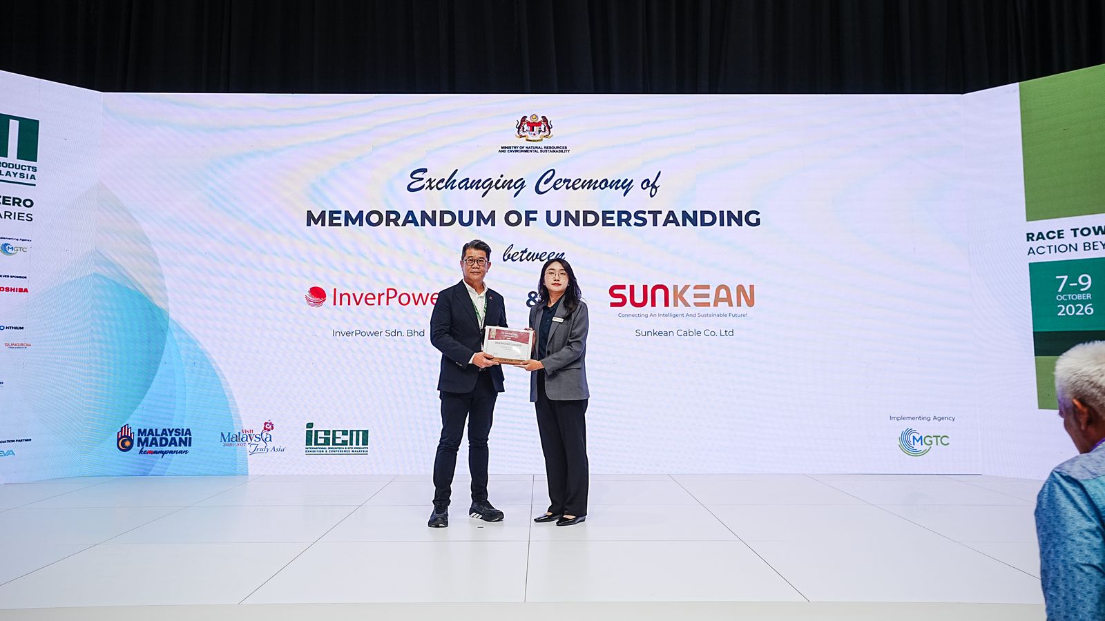 InverPower and Sunkean Cable representatives exchanging an MOU on stage at the MGTC Arena, iGEM 2026