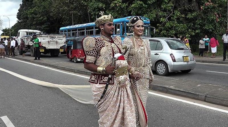 About 250 students of a state-owned school carried the train of the 3.2-kilometre (two-mile) long saree worn by the bride as she and the groom walked down a main road in the central district of Kandy on Thursday, local media reported. (Photo: AFP)