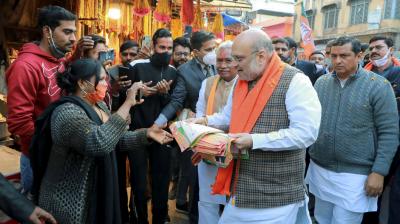 Union Home Minister Amit Shah distributes pamphlets during his door-to-door campaign for the Uttarakhand Assembly elections, in Haridwar. (PTI Photo)