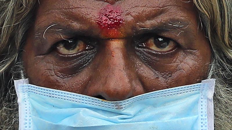 A farmer wearing a face mask listens to a speaker during an anti-government protest in Bengaluru. (AP)