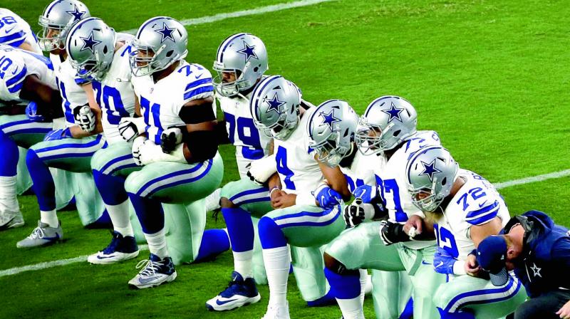 The Dallas Cowboys team go down on their knees during the national anthem prior to an NFL game against the Arizona Cardinals in Glendale, USA. (Photo: AP)