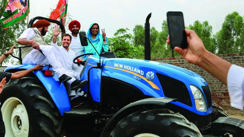 Congress chief Rahul Gandhi waves from the drivers seat of a tractor during a poll campaign in Ludhiana on Wednesday. (Photo: PTI)