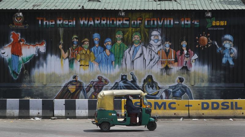 An auto rickshaw drives past a mural depicting frontline workers fighting against COVID-19 in New Delhi. AP Photo