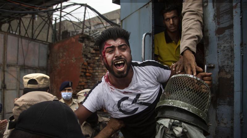 Policemen detain a Kashmiri Shiite Muslim as he attempts, along with others, to take out a religious procession in Srinagar