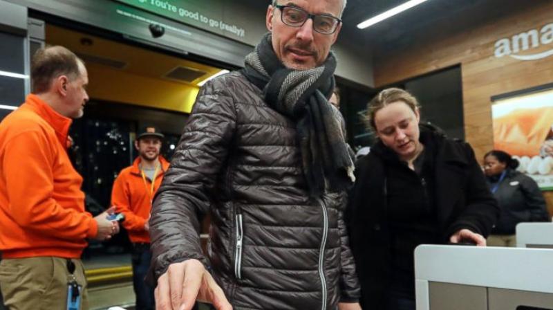 A customer scans his Amazon Go cellphone app at the entrance as he heads into an Amazon Go store in Seattle. One firm building automated checkout systems, AVA Retail, said Thursday, June 14 that it is working with Microsoft on the technology for physical stores. (AP Photo/Elaine Thompson, File)