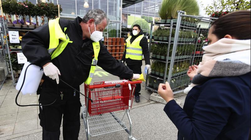 A security employee disinfects shopping carts at the entrance of a garden store in Munich, Germany, Monday. AFP Photo