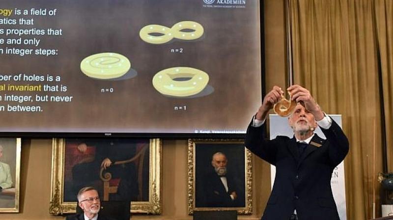 Professor Thors Hans Hansson gives a demonstration using a bagel to explain the work of the winners of the Nobel Prize in physics, at the Royal Swedish Academy of Sciences, in Stockholm, Sweden. (Photo: AP) Professor Thors Hans Hansson gives a demonstration using a bagel to explain the work of the winners of the Nobel Prize in physics, at the Royal Swedish Academy of Sciences, in Stockholm, Sweden. (Photo: AP)