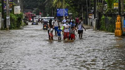 Residents wade through a flooded street after heavy monsoon rains at Biyagama, on the outskirts of Colombo. (Photo: AFP)