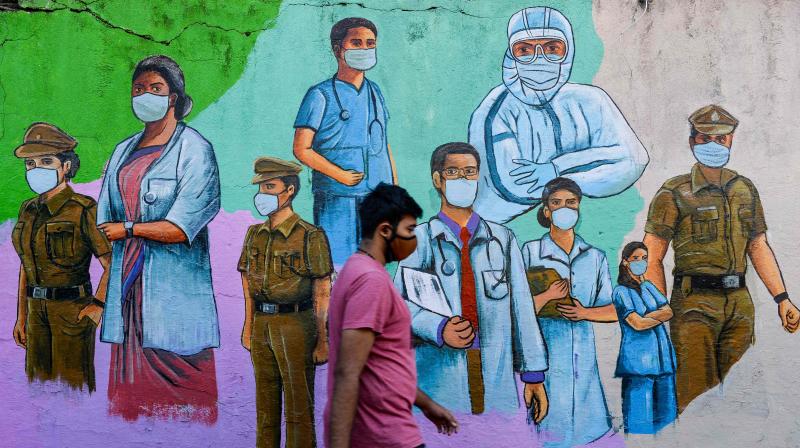 pedestrian walks past a wall mural featuring illustrations of frontine workers urging citizens to wear masks properly in order to raise awareness about the Covid-19 coronavirus in Mumbai. (Photo: AFP)