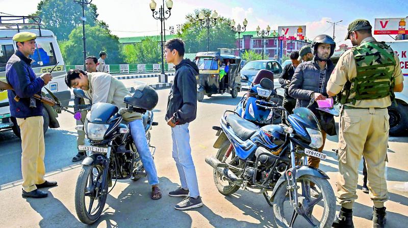 Security personnel check documents of motorcyclists during a shut down in Srinagar on Sunday. (PTI) Security personnel check documents of motorcyclists during a shut down in Srinagar on Sunday. (PTI)