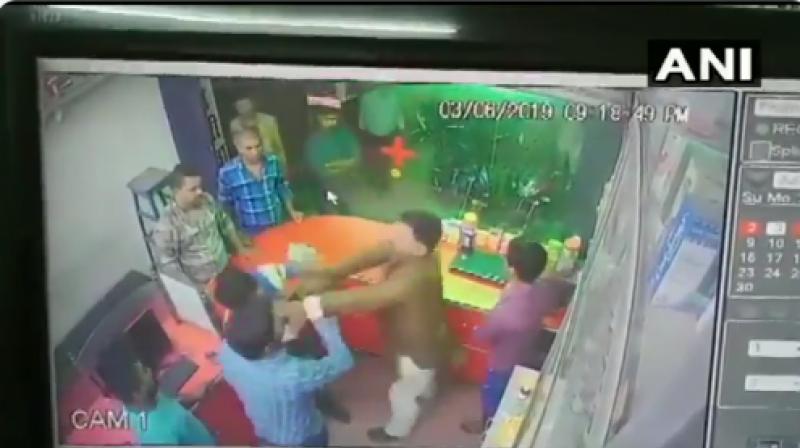 When the chemist refused to stand up, the ex-minister's brother slapped him and dragged him outside the shop by his collar. Pinu later was seen taking the chemist away in a car. (Photo:Twitter I ANI) When the chemist refused to stand up, the ex-minister's brother slapped him and dragged him outside the shop by his collar. Pinu later was seen taking the chemist away in a car. (Photo:Twitter I ANI)