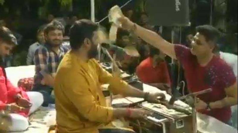 In Thursday's devotional programme, folk singer Brijraj Gadhvi was showered with wads of currency notes in the denominations of Rs 10-500. (Screengrab | ANI) In Thursday's devotional programme, folk singer Brijraj Gadhvi was showered with wads of currency notes in the denominations of Rs 10-500. (Screengrab | ANI)