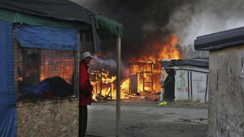 A man stands next to a burning tent as fires were started in the makeshift migrant camp known as "the jungle" near Calais, northern France .(Photo:AP) A man stands next to a burning tent as fires were started in the makeshift migrant camp known as "the jungle" near Calais, northern France .(Photo:AP)