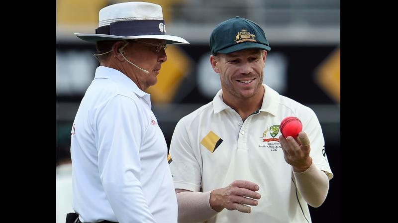 David Warner (R) discusses the balls shape with umpire Ian Gould during the day-night cricket Test againist Pakistan in Brisbane. AFP Photo