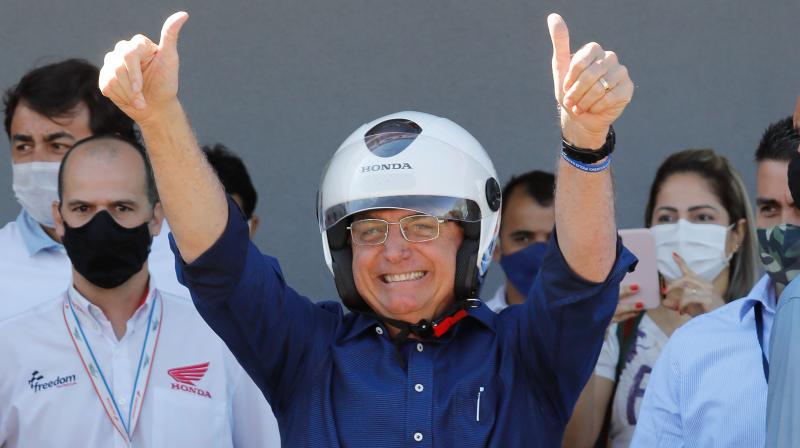 Brazilian President Jair Bolsonaro gestures after going out for a ride and having his motorcycles engine overhaul after he announced he tested negative for COVID-19 more than two weeks after being diagnosed, in Brasilia. (AFP)