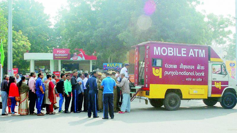 People queue up to withdraw money from a mobile ATM at ITPO, Pragati Maidan in New Delhi on Monday. In an attempt to reduce rush at bank branches and ATMs, banks have pressed into service mobile ATM vans. (Photo: PTI) People queue up to withdraw money from a mobile ATM at ITPO, Pragati Maidan in New Delhi on Monday. In an attempt to reduce rush at bank branches and ATMs, banks have pressed into service mobile ATM vans. (Photo: PTI)