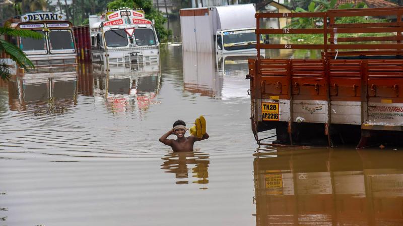 A person stands near submerged trucks on a waterlogged street at a flood-affected region following heavy monsoon rainfall, in Kochi on Thursday. (Photo: PTI) A person stands near submerged trucks on a waterlogged street at a flood-affected region following heavy monsoon rainfall, in Kochi on Thursday. (Photo: PTI)