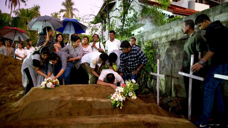 Relatives place flowers after the burial of three victims of the same family, who died at Easter Sunday bomb blast at St Sebastian Church in Negombo. (Photo: AP) Relatives place flowers after the burial of three victims of the same family, who died at Easter Sunday bomb blast at St Sebastian Church in Negombo. (Photo: AP)