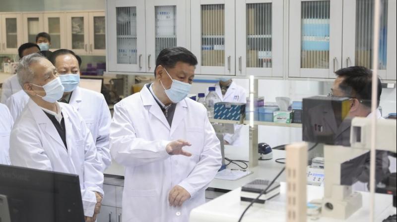 In this photo released by Xinhua News Agency, Chinese President Xi Jinping, centre, wearing a protective face mask, talks to a medical staff member during his visit to the Academy of Military Medical Sciences. AP Photo