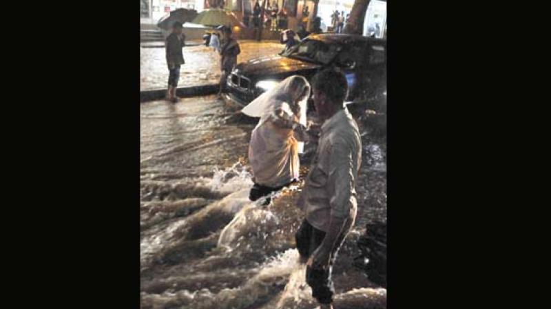 A yougester helps a woman cross the water-logged road at Shivananda Circle in Bengaluru on Friday (Photo: KPN) A yougester helps a woman cross the water-logged road at Shivananda Circle in Bengaluru on Friday (Photo: KPN)