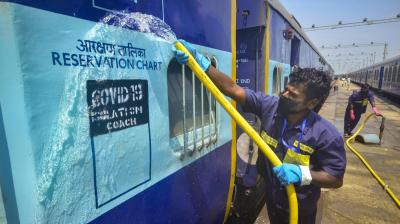 A worker washes a train coach to be converted into isolation ward for COVID-19 patients. (PTI)