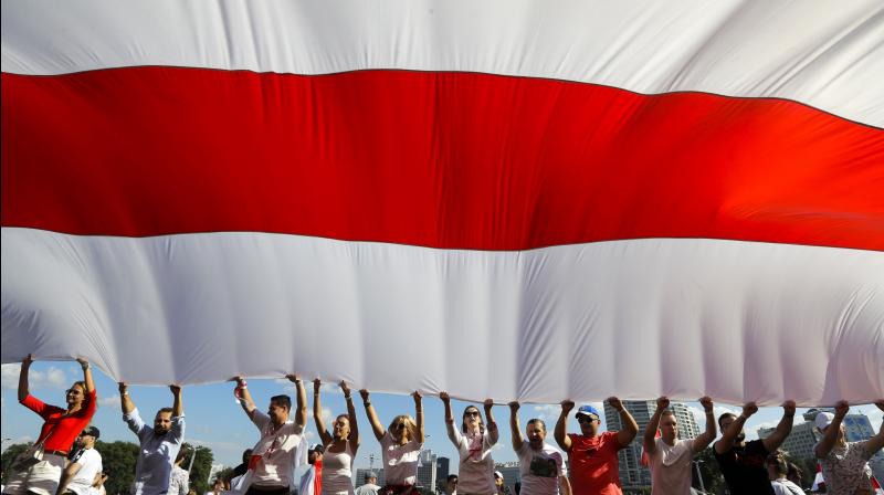 Opposition supporters wave a huge old Belarusian national flag as they rally in the center of Minsk, Belarus. AP Photo