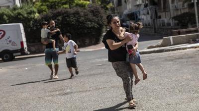 Lia Tal, 40, rushes with her children and partner to take shelter as a siren sounds a warning of incoming rockets fired from the Gaza Strip, In Ashdod, Israel, Thursday, May 20, 2021. (AP/Heidi Levine)