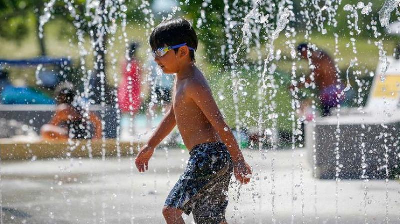 A child runs through a fountain at a splash park trying to beat the heat in Calgary, Alberta, on June 30, 2021.  (AP)