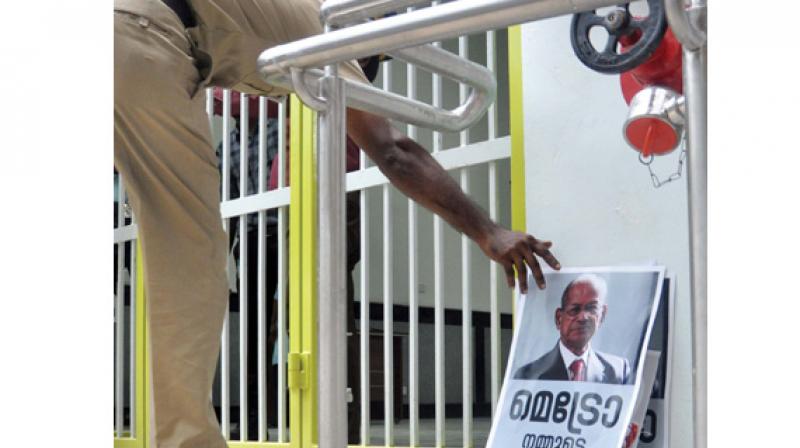 A police official places a poster on E. Sreedharan in a corner at a Kochi Metro station on Thursday. (Photo: DC) A police official places a poster on E. Sreedharan in a corner at a Kochi Metro station on Thursday. (Photo: DC)