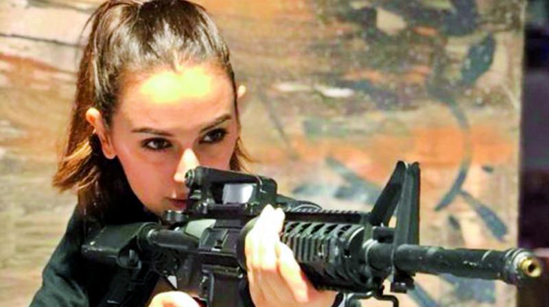 The picture shows Evelyn holding a gun in an action sequence. The picture shows Evelyn holding a gun in an action sequence.