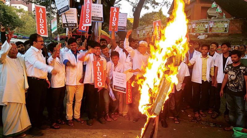 Medicos burn the effigy of the NMC Bill in a protest held at Mysore Bank Circle in the city on Tuesday. (Photo: DC) Medicos burn the effigy of the NMC Bill in a protest held at Mysore Bank Circle in the city on Tuesday. (Photo: DC)
