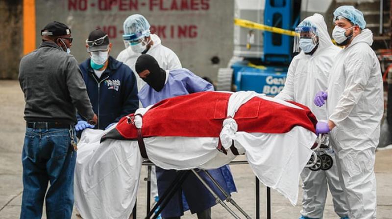 A body wrapped in plastic that was unloaded from a refrigerated truck is handled by medical workers wearing personal protective equipment at Brooklyn Hospital Center in New York City (AP Photo)