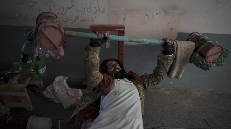 A Taliban fighter lifts a makeshift weight left behind by former prisoners at an empty area of the Pul-e-Charkhi prison in Kabul, Afghanistan. (Photo: AP) A Taliban fighter lifts a makeshift weight left behind by former prisoners at an empty area of the Pul-e-Charkhi prison in Kabul, Afghanistan. (Photo: AP)