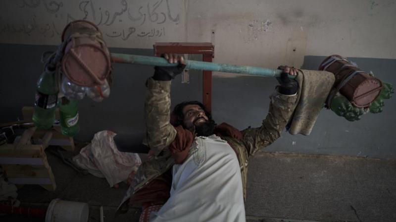 A Taliban fighter lifts a makeshift weight left behind by former prisoners at an empty area of the Pul-e-Charkhi prison in Kabul, Afghanistan. (Photo: AP)